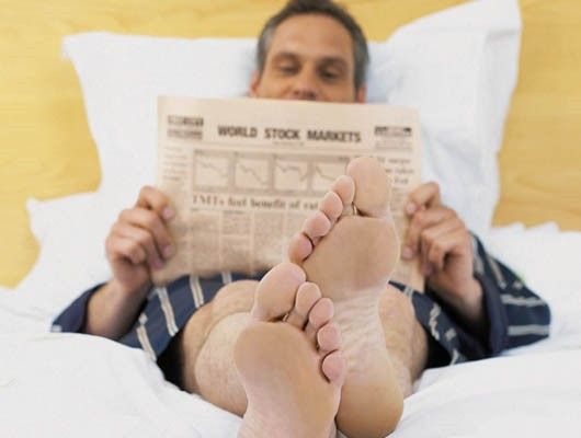 Hombre en la cama leyendo el periódico